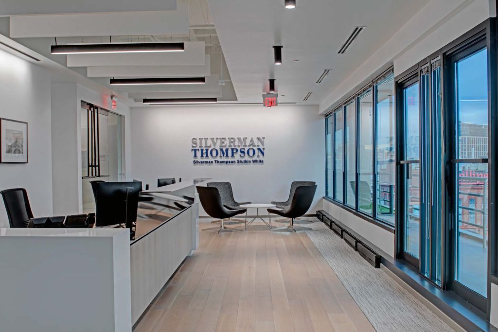 A reception desk and waiting area under a Silverman Thompson sign